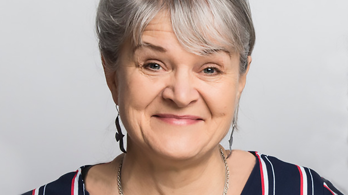 Cheryl L’Hirondelle, wearing silver bird earrings, smiles.